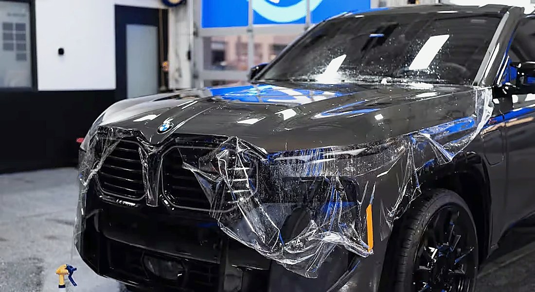Paint protection film being installed on a dark BMW SUV