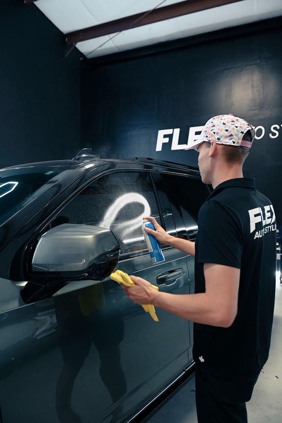 A FLEX installer cleaning a car window before tinting